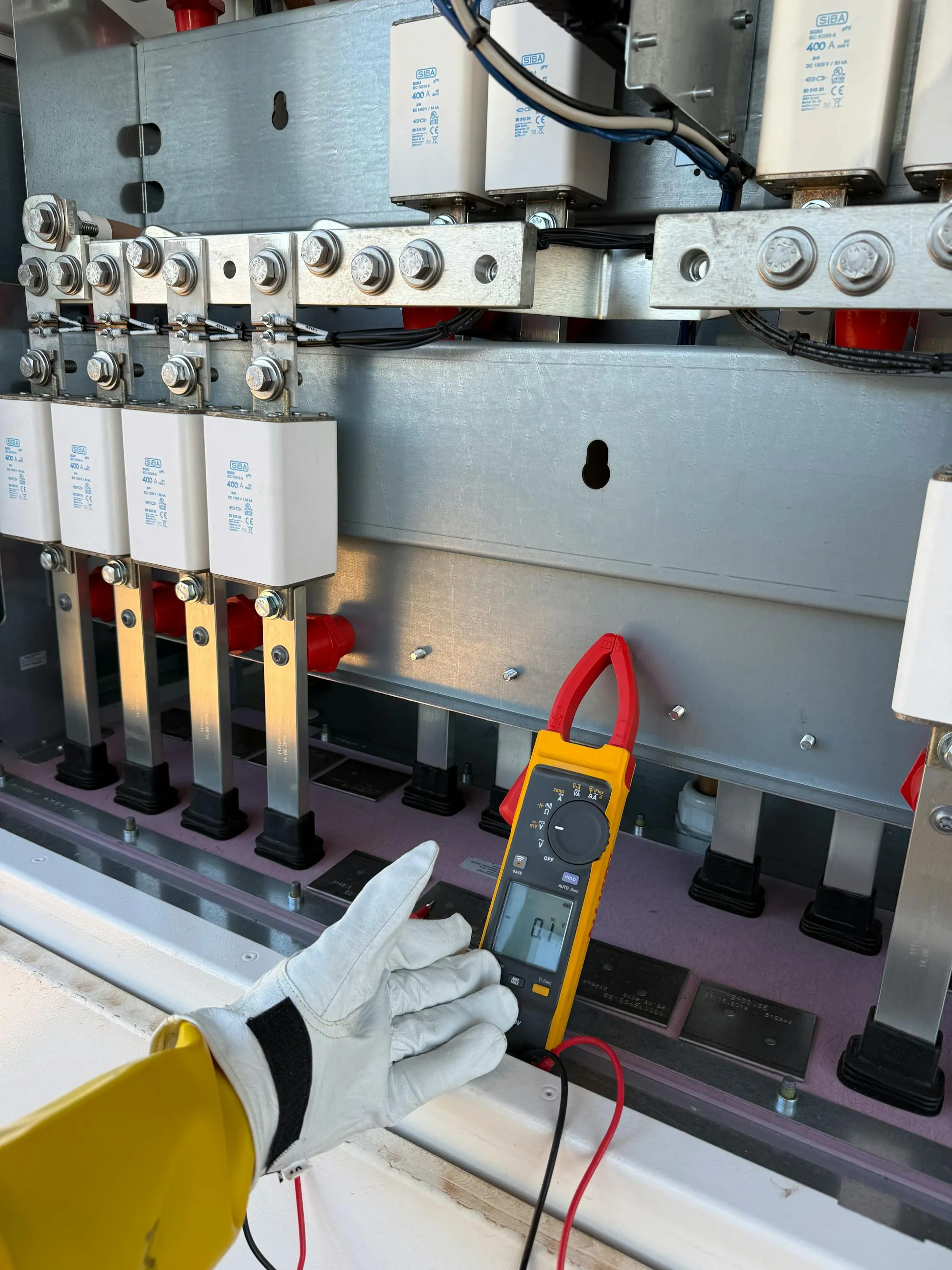 Clamp meter testing live busbar inside an electrical panel